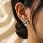 Silver bow stud earrings with dangling crystal heart