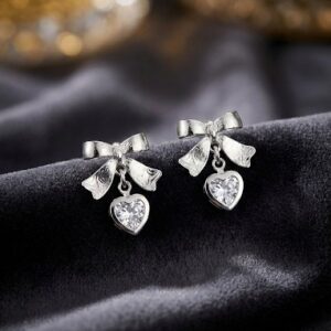 Silver bow stud earrings with dangling crystal heart