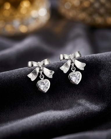 Silver bow stud earrings with dangling crystal heart